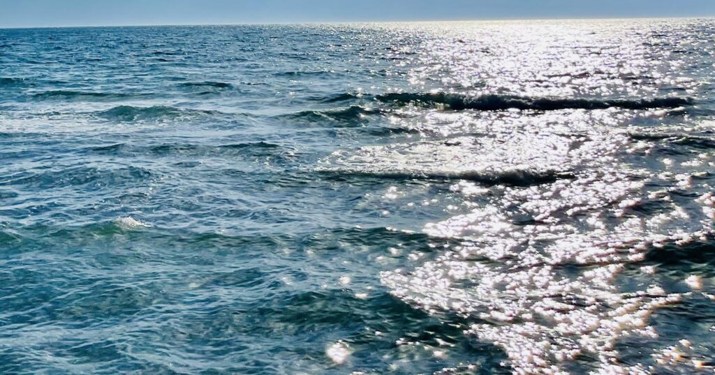 The blue green of the Pacific ocean waves dance in the light of the sun.